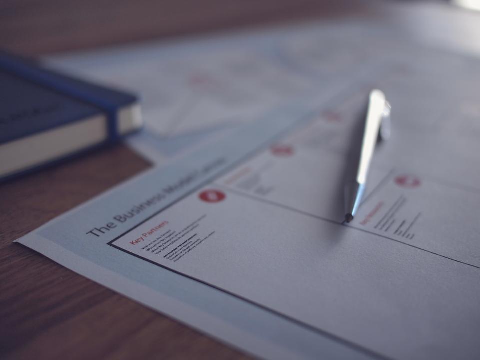 A cheque book, pen and printed papers on an office desk