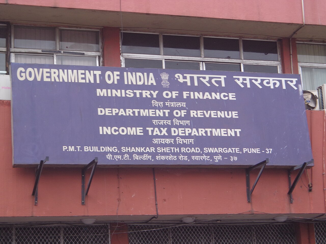 Purple signboard on a red building reading Government of India, Income Tax Department, Pune